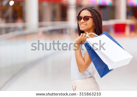 Live fully. Nice beautiful upbeat girl keeping packages on the shoulder and shopping  while walking through the mall