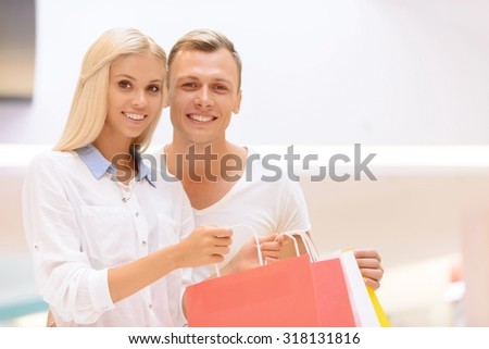 Spending time together. Nice jubilant smiling young couple holding packages and bonding to each other while feeling delighted.