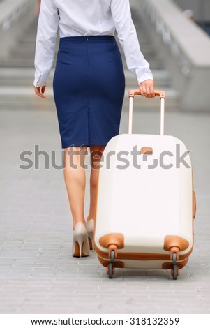 It is a nice journey. Pleasant attractive young woman holding suit case and going with it while being turned back