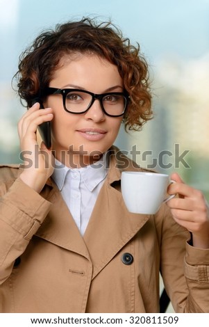 Nice to hear you. Nice beautiful positive girl talking on mobile phone and holding cup of coffee while drinking it