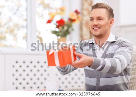 Want to make you happy. Blissful handsome young man presenting gift and having cozy dinner