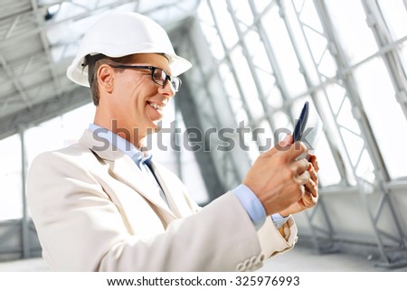 Like my job. Agreeable upbeat smiling architect holding laptop and using it while being involved in work