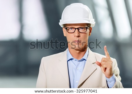 Listen to me. Rigorous serious professional architect holding his finger up and drawing your attention while being at work