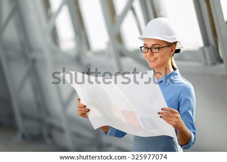 Ready to work. Cheerful delightful pleasant female architect hlding plan and studying it while being involved in work