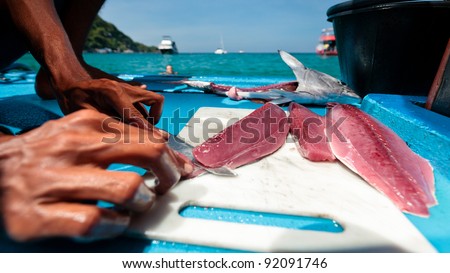 Thai Fishermen cleaning and filleting a fresh tuna aboard a deep sea fishing boat. Prepares tuna sashimi.