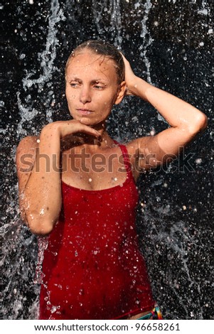 Nature spa concept - Young and emotional girl in red tank-top enjoying jungle waterfall