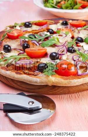 Pizza with dry cured ham and salad