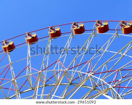 Big Ferris wheel with colored cabins on cloudy sky