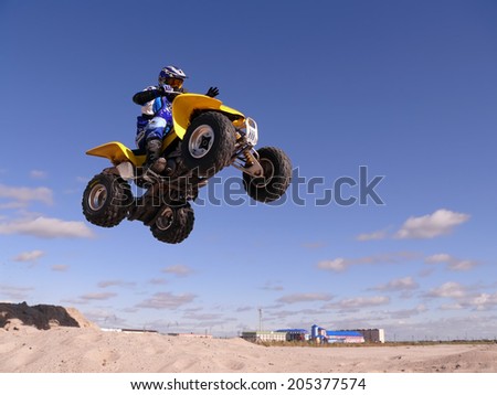 Nadym, Russia - August 26, 2007: Extreme sport. Vadim Vasyuhin in jumping on an  quadrocycle. View of the city. Homes.