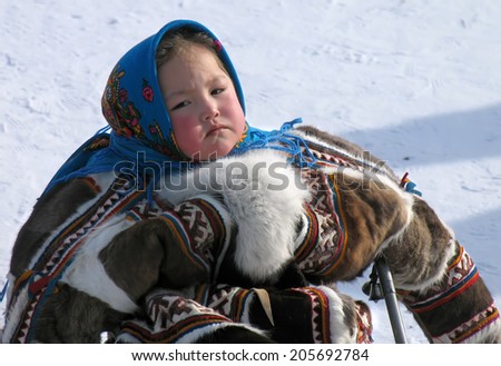 Nadym, Russia - March 18, 2006: the national holiday, the day of the reindeer herder in Nadym, Russia - March 18, 2006. Unknown girl in the Nenets woman on a sledge.