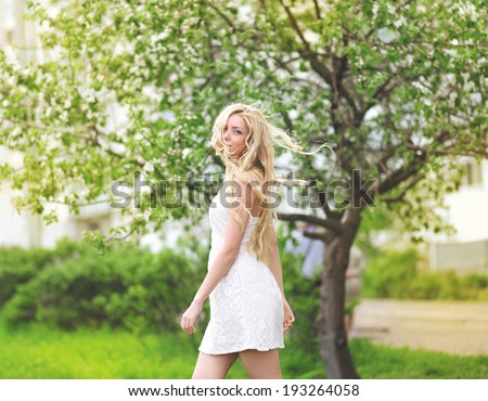 Pretty woman with curly hair in spring garden, sunny day