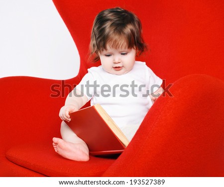 Baby and book on red chair