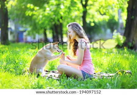 Happy girl and dog having fun in summer sunny park, dog gives paw owner
