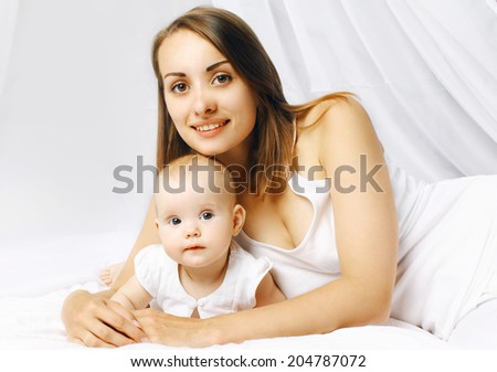 Portrait happy baby and mom in bed