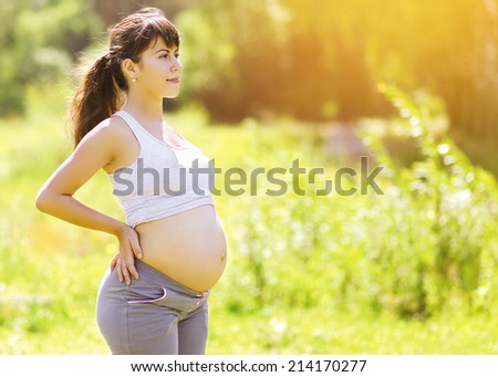 Young pregnant woman looking and dreams outdoors in sunny summer day