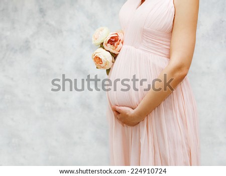 Pregnancy, motherhood and happy future mother concept - pregnant woman and bouquet flowers