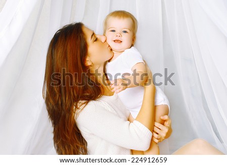 Mom kiss lovely baby in bed home