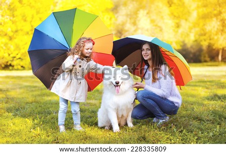 Family, leisure, weather and people concept - mother with child and dog walks with umbrellas outdoors in autumn day