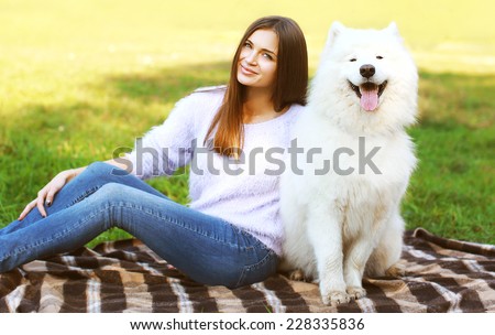 Beautiful happy woman owner and dog resting on the plaid outdoors in warm sunny day