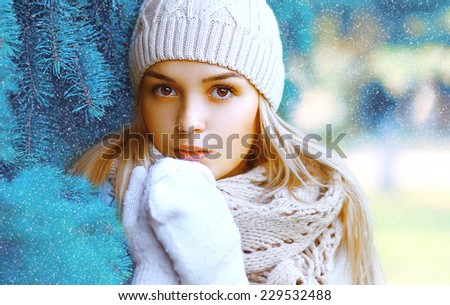 Christmas, winter and people concept - portrait pretty girl in hat closeup near the Christmas tree branches in winter snowy day