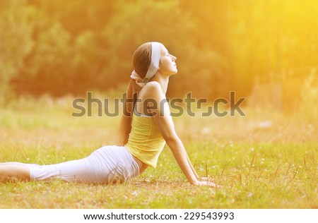 Sport, fitness, yoga - concept, slim woman doing exercise outdoors on the grass