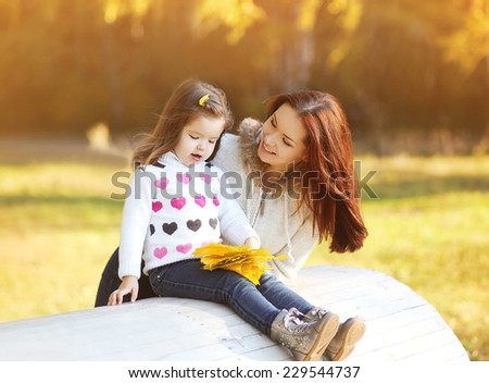 Happy mom and daughter having fun outdoors in autumn park