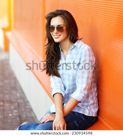 Summer, fashion and people concept - portrait modern stylish pretty woman in sunglasses and casual clothes posing outdoors against colorful wall in city