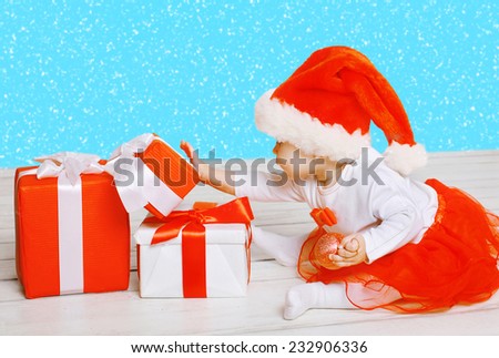 Christmas and people concept - child playing with a gifts and snowflakes