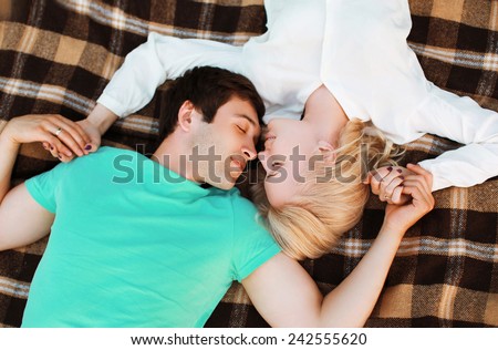 Lovely young couple in love resting on the plaid, warm tender feelings. Top view