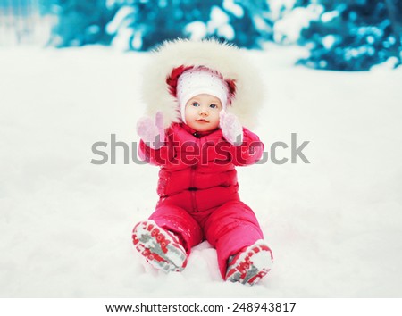 Sweet baby sitting on the snow in winter day