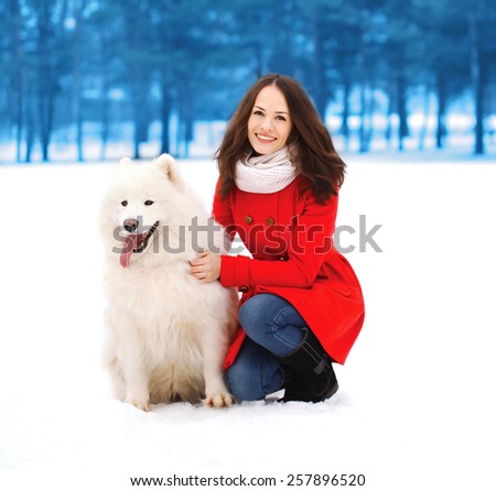Winter, christmas and people concept - happy woman having fun with white Samoyed dog outdoors in winter day