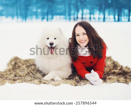 Winter, christmas and people concept - happy woman having fun with white Samoyed dog outdoors on the snow in winter day