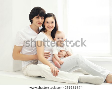 Portrait of happy young family at home in white room near window