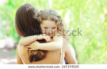 Mother\'s day, family, childhood and people concept - happy daughter hugging mother in warm sunny summer day on the nature