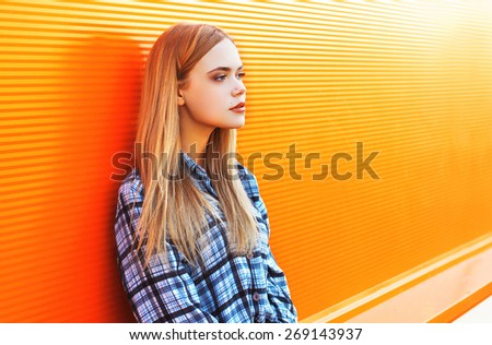 Outdoor fashion portrait of pretty woman in the city against the colorful orange wall