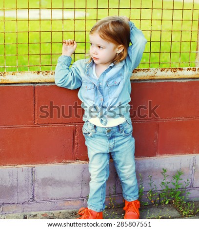 Portrait of stylish little girl child in the jeans clothes outdoors