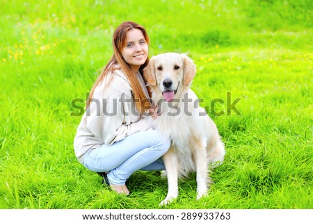 Portrait of happy owner and Golden Retriever dog together on the grass in sunny summer day