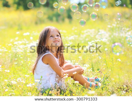 Child sitting on the grass dreaming in sunny summer day