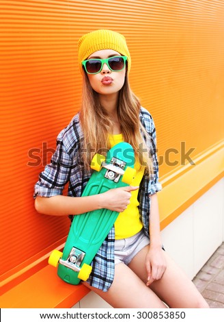 Fashion portrait of hipster cool girl in sunglasses and colorful clothes with skateboard having fun outdoors
