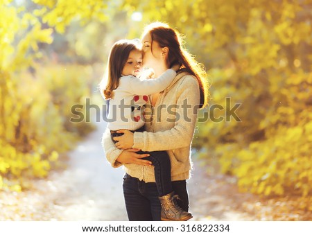 Happiness mother! Mom kissing child in sunny autumn park