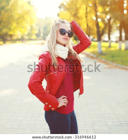 Fashion young woman wearing a red leather jacket with scarf in autumn park