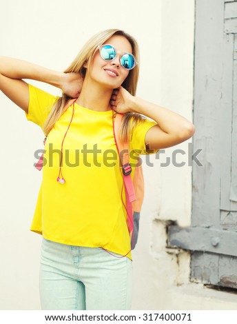 Pretty smiling blonde woman wearing a sunglasses and yellow t-shirt in the city, street fashion