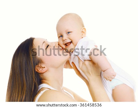 Happy Mother Holding On Hands And Kissing Her Cute Baby Over White