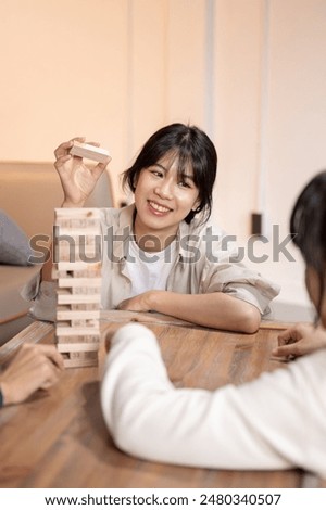 Similar – Image, Stock Photo Excited girl playing jenga game with her mom in play room. Girl removing one block from stack and placing it on top of tower. Game of skill and fun. Family time