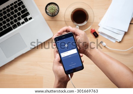 A man hand holding screen of Facebook app on Apple iPhone 6 plus. Facebook is largest and most popular social networking site in the world.CHIANG MAI ,THAILAND - JULY 31, 2015