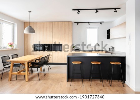 Modern interior of kitchen with kitchen island, granite kitchen island, wooden furnitureand stylish table and chairs. Spacious and luxurious space in apartment. 