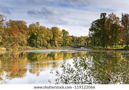 River in autumn day with the stone bridge and trees reflection