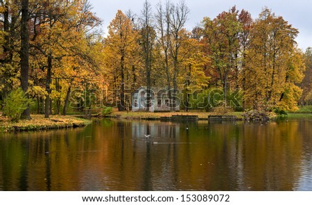 Pond with park pavilion and beautiful autumn trees in the park