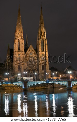 St.Paul Cathedral in the dark next to Strasbourg Ill river and illuminated bridge over it