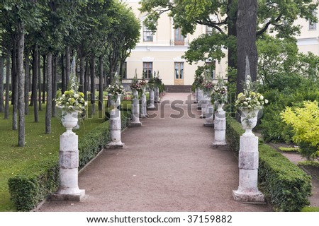 The way with vases in the garden leading to classical building